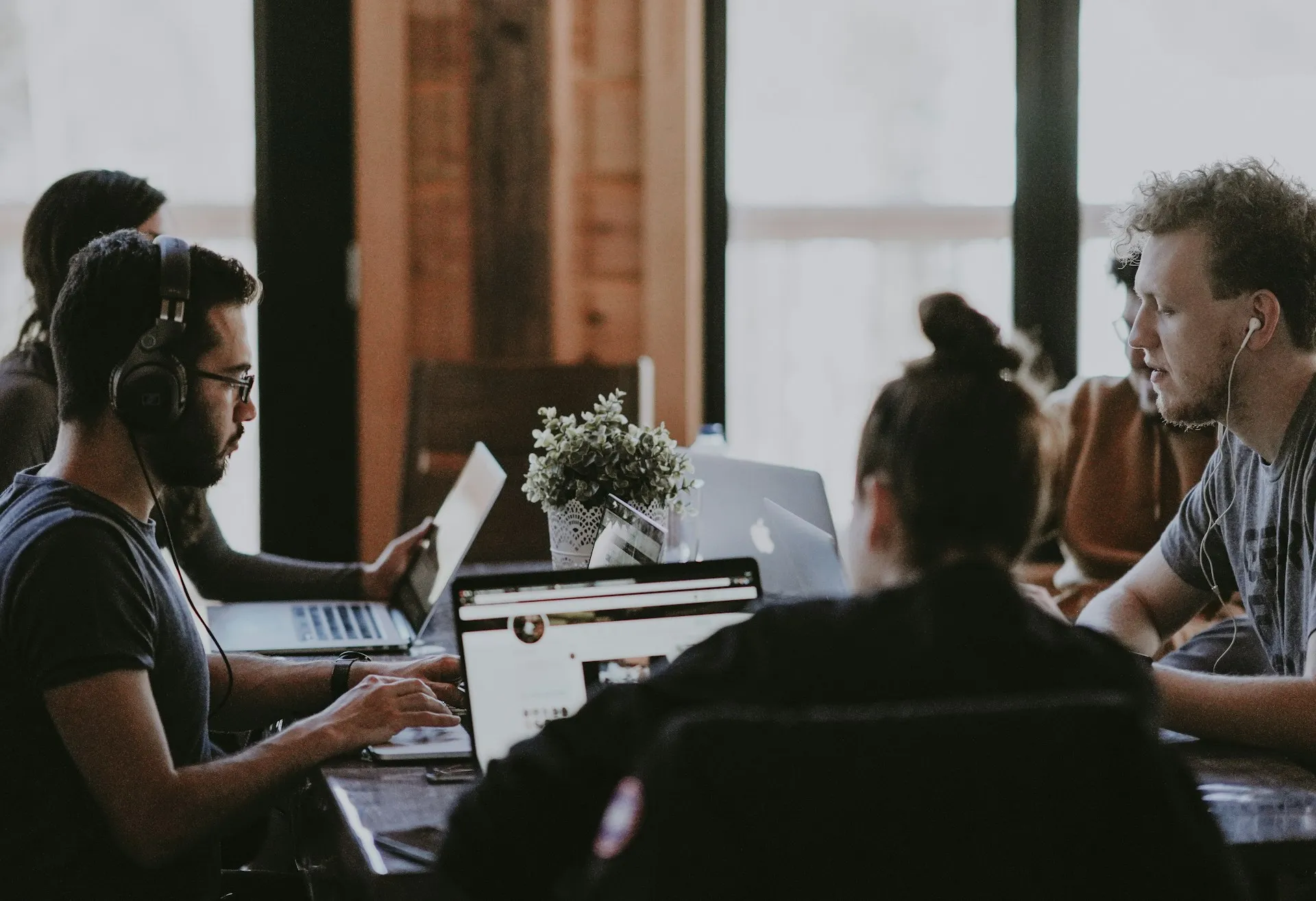 A group of people sitting at a table with laptops.