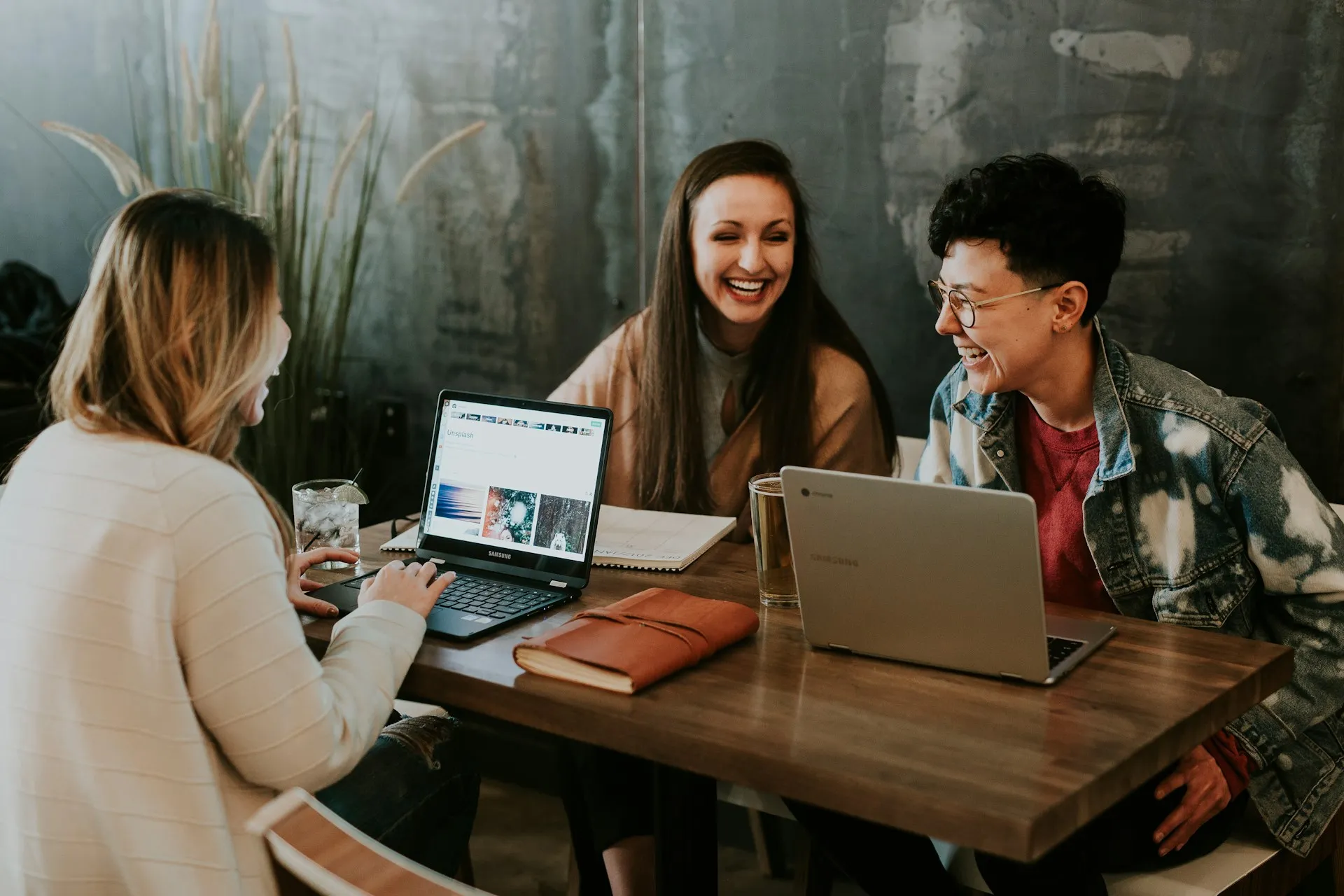 A group of people sitting around a table with laptops.